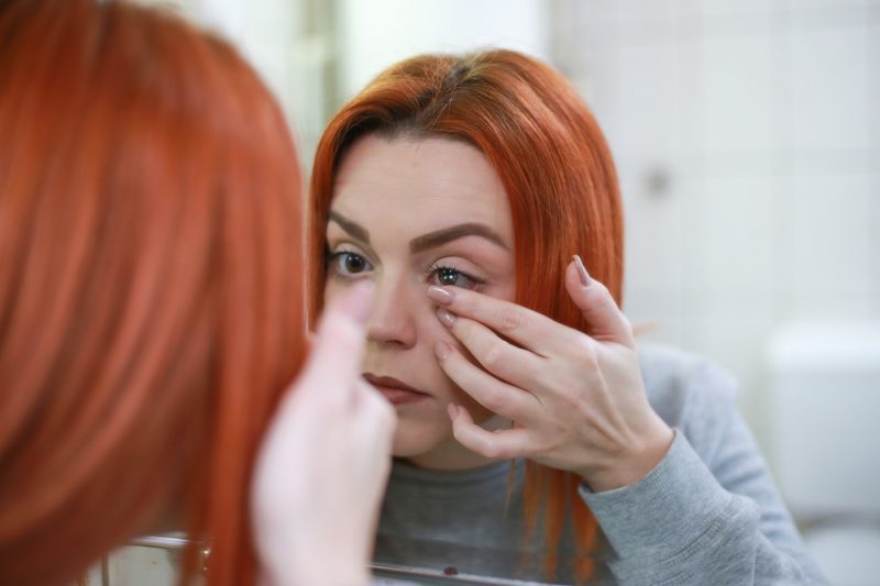 Mulher ruiva coloca lente de contato para miopia e astigmatismo