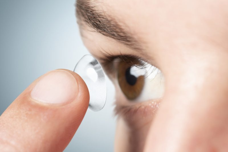 Homem insere lentes de contato nos olhos