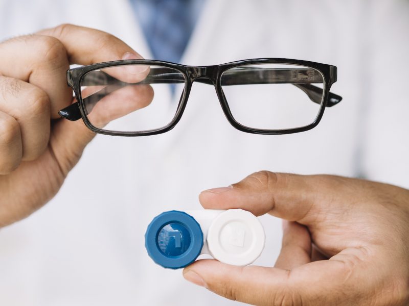 Médico segura óculos de grau e estojo de lentes de contato