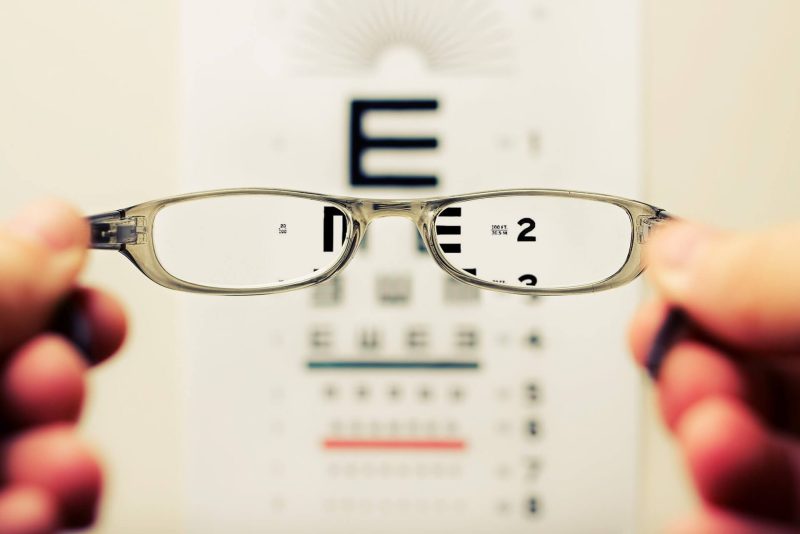 Óculos com lente monofocal em frente ao quadro oftalmológico para explicar o que é pl na receita
