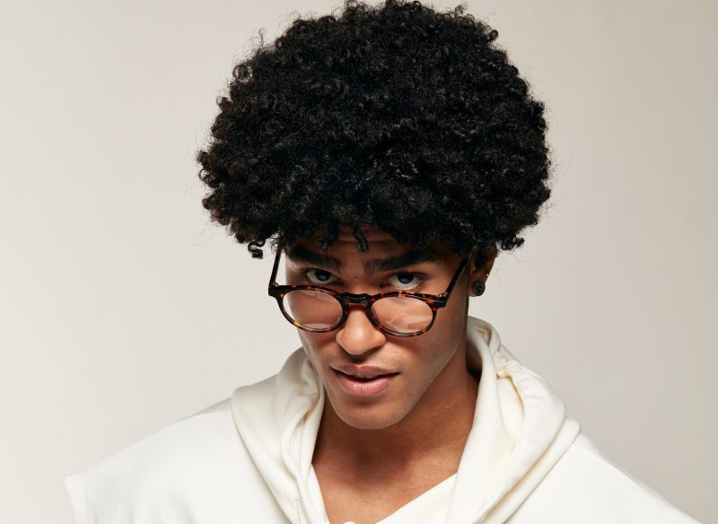 homem negro com cabelo black power usa óculos para 0.50 de astigmatismo