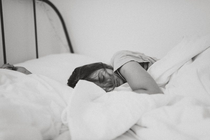 Mulher em preto e branco dorme na cama com lentes de contato