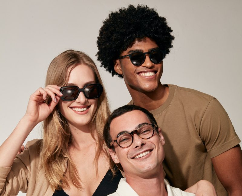 Dois homens e uma mulher usam modelos de óculos de sol e de grau da LIVO