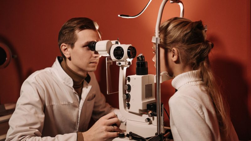 Oftalmologista examinando os olhos de menina em seu escritório